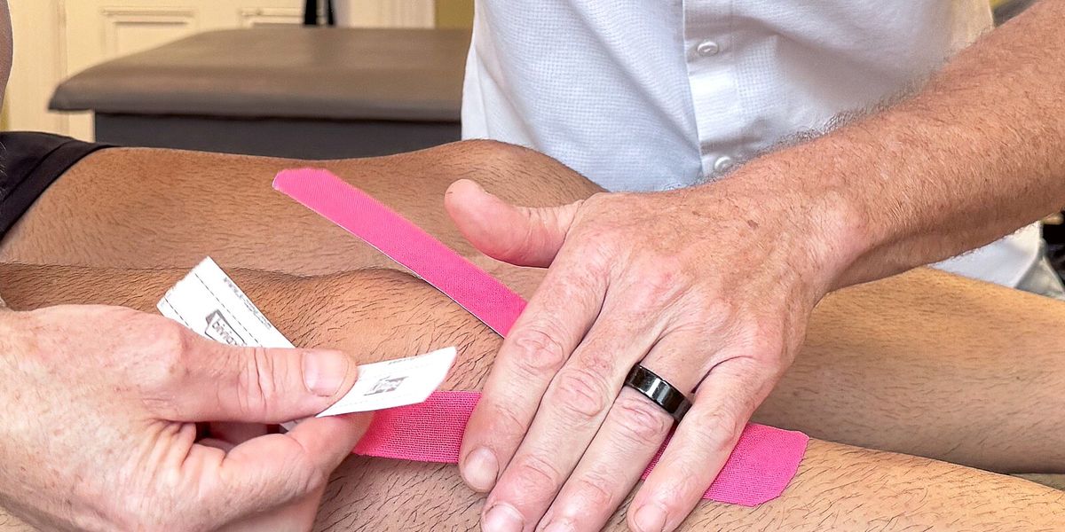 Mark applying kinesiology tape to an athlete's knee